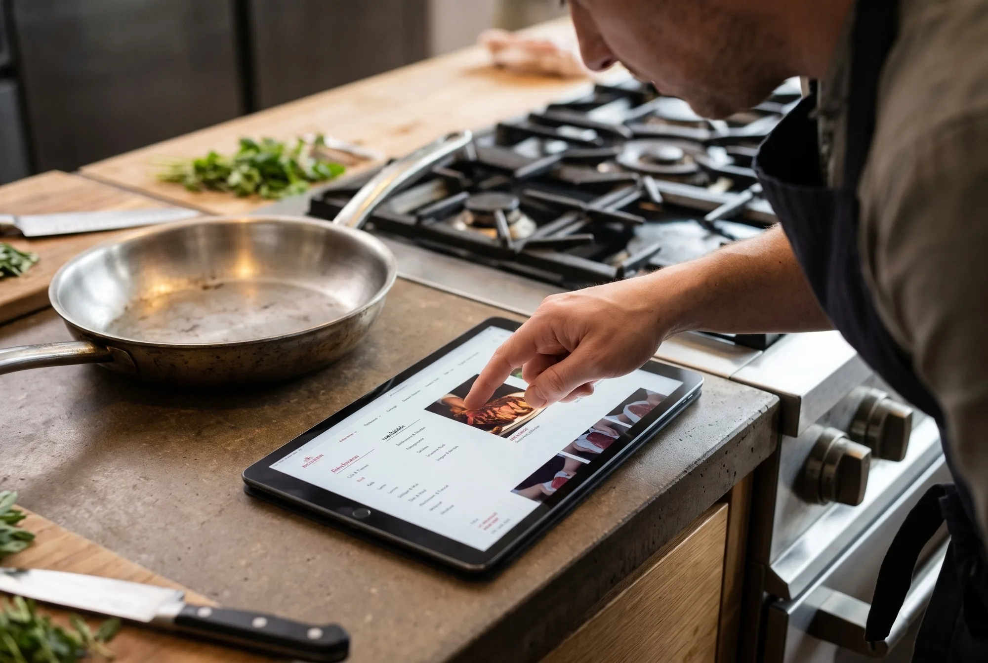 Koch wählt in der Küche auf dem Tablet eine Kategorie im BEISSER-Onlineshop